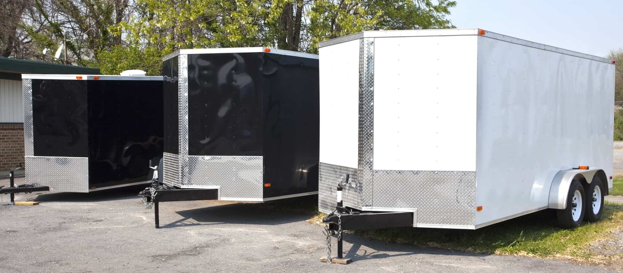 Row of new enclosed cargo trailers lined up on a dealer lot